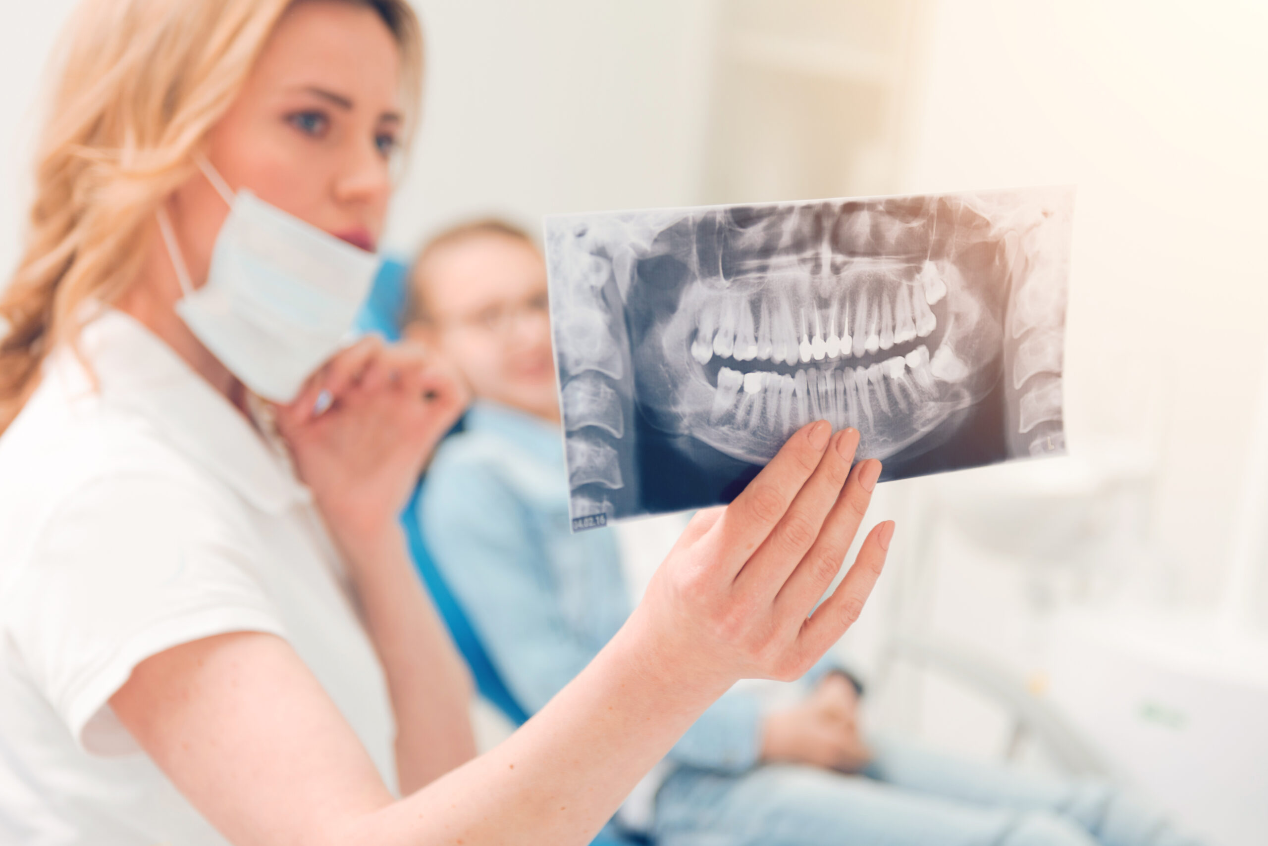 Have a look. Selective focus on an x ray scan picture of patient jaws held by a female sitting next to a child patient and showing her the scan